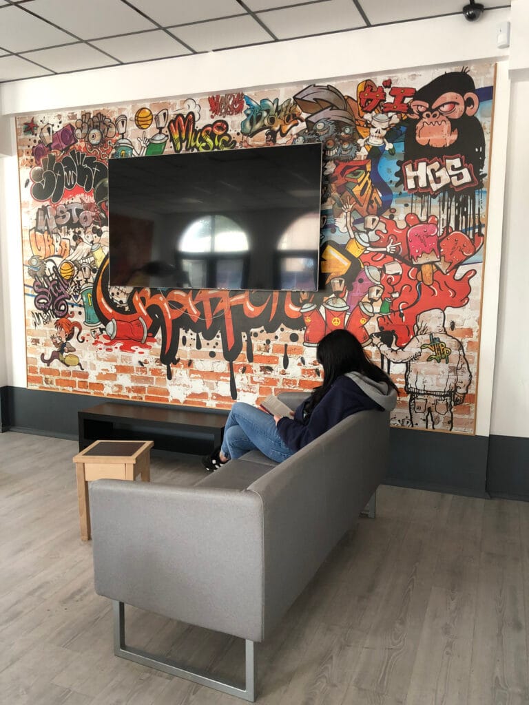 un coin de la maison des lycéens avec des grafitis, une télévision et un canapé