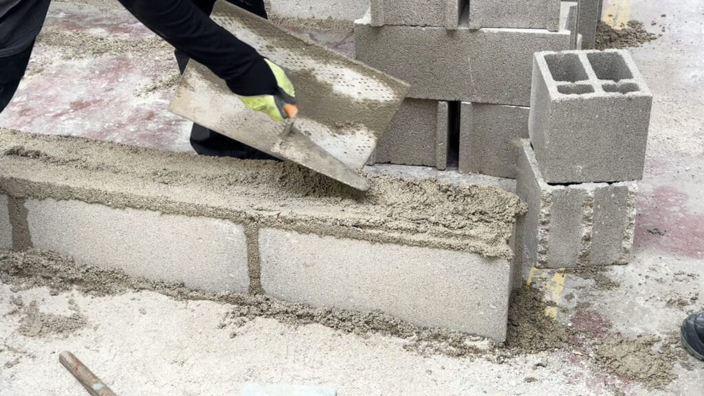 un élève qui cimente un parpaing