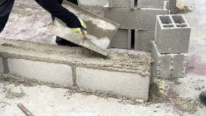 un élève qui cimente un parpaing